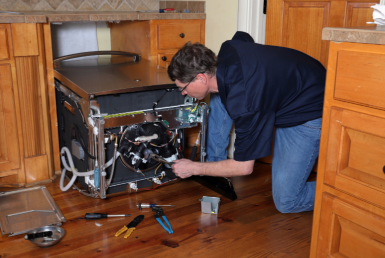 A guy fixing a dishwasher.
